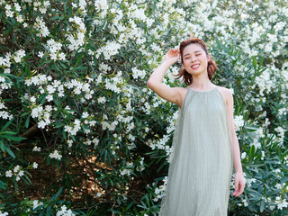 Portrait of young Asian woman standing in white oleander flower forest background, beautiful...