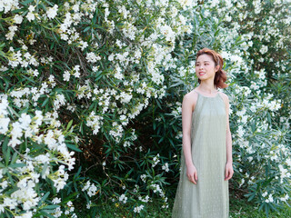 Portrait of young Asian woman standing in white oleander flower forest background, beautiful...