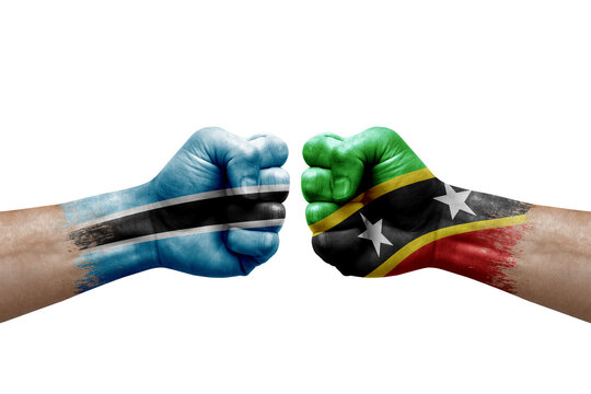 Two hands punch to each others on white background. Country flags painted fists, conflict crisis concept between botswana and saint kitts and nevis