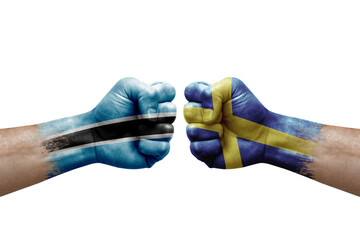 Two hands punch to each others on white background. Country flags painted fists, conflict crisis concept between botswana and sweden