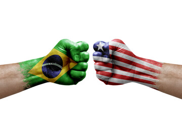 Two hands punch to each others on white background. Country flags painted fists, conflict crisis concept between brazil and liberia