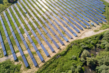 Aerial view of solar power plant on green field. Electric farm with panels for producing clean ecologic energy