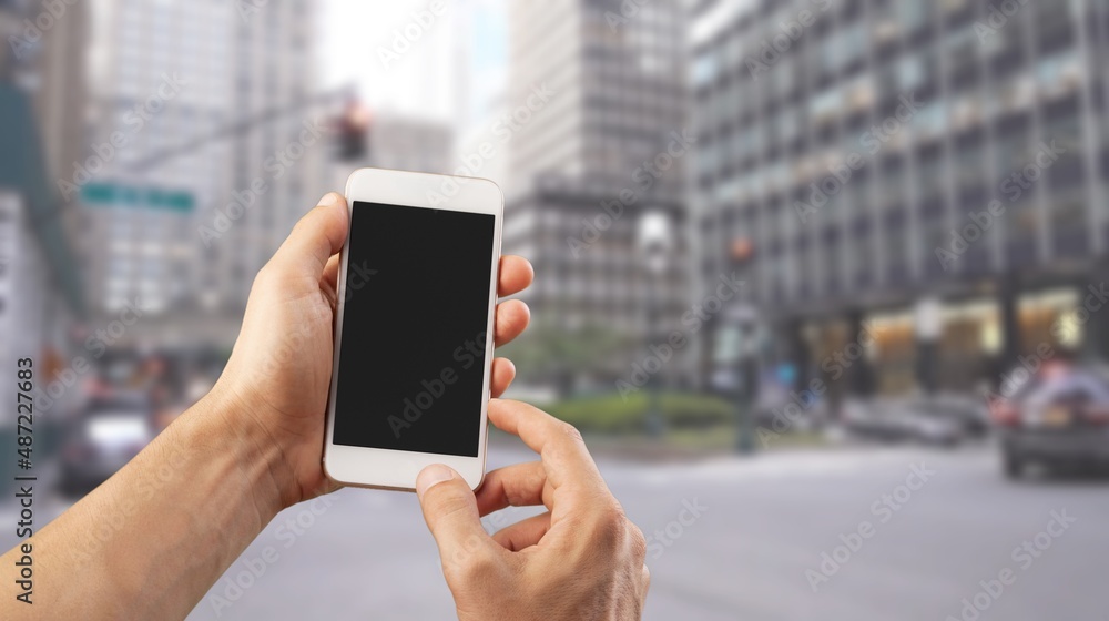 Poster Human hand holding phone with blank screen and cityscape blur background