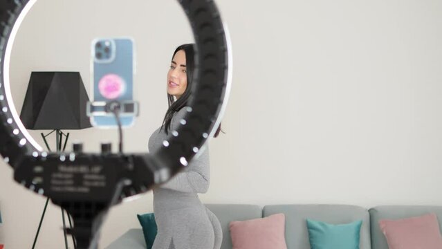 Virtual online fitness. Woman virtual workout at home living room. Fitness stretching exercises online women at home with smartphone. Attractive Woman personal trainer coach recording on camera new