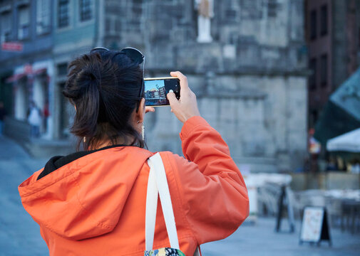 A closeup of a young woman from behind taking pictures on her phone