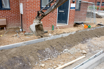 Construction workers finishing construction of new residential house and installing footpath in...