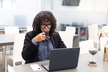 Brown and curly young woman working with a laptop on a desk