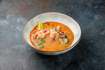 Tom Yam soup with seafood, shrimps, squid, mussels on dark stone table