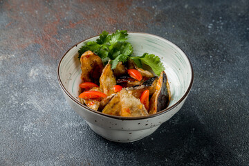 fried eggplant in sweet sour sauce with tomatoes on dark stone table