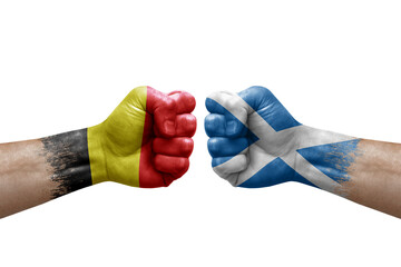 Two hands punch to each others on white background. Country flags painted fists, conflict crisis concept between belgium and scotland