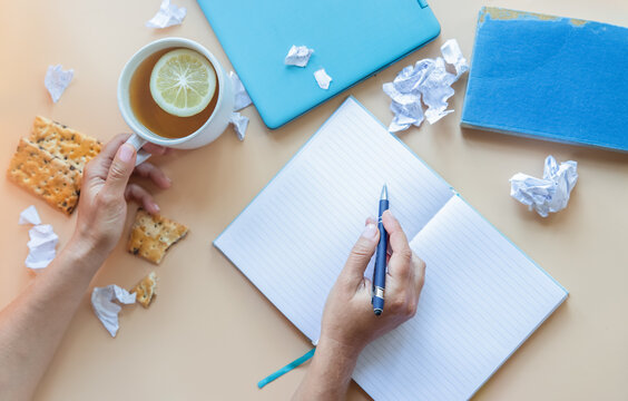 Flatlay Of Home Office Or Working Space With Notebook, Book, Cup Of Tea And Cookies. Draft Paper On The Background. Working Or Thinking Process Concept