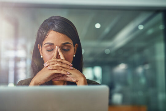 Feeling drained from all her efforts. Shot of a young businesswoman looking stressed out while working in an office.