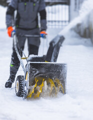 Process of removing snow with portable blower machine, worker dressed in overall workwear with gas snow blower removal on the street during winter