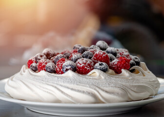 meringue cake with blueberries and raspberries on a plate on green background
