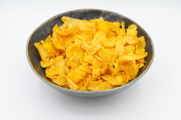 Corn Flakes, in a dark grey bowl, isolated on a white background
