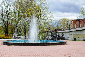 Splashes of a jet of a fountain in a city square against a blue sky
