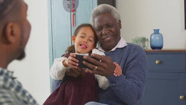 Grandfather with grandchildren playing game on mobile phone at home - shot in slow motion