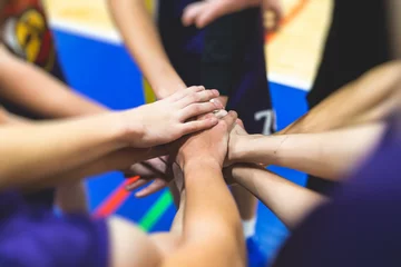Fotobehang Team of kids children basketball players stacking hands in the court, sports team together holding hands getting ready for the game, playing indoor basketball, team talk with coach, close up of hands © tsuguliev
