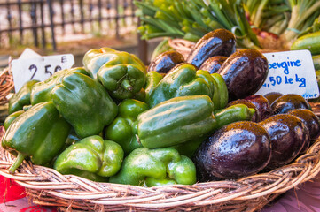 Fresh eggplant and green pepper vegetables in a basket at a French farmer's market