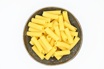 Raw Tortiglioni pasta, in a dark grey bowl, isolated on a white background
