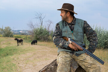 Hunter man in camouflage with a gun during the hunt in search of wild birds or game. Autumn hunting...