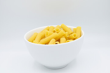 Raw Tortiglioni pasta, in a white bowl, isolated on a white background 