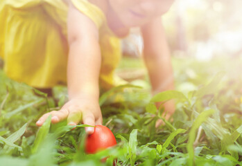 Child reaching for a red easter egg