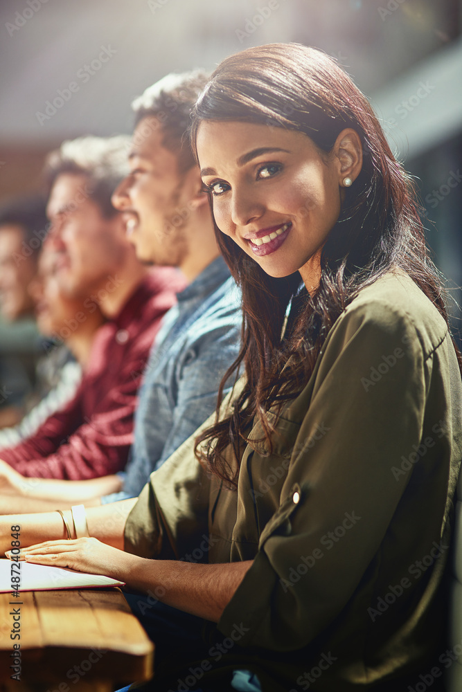 Poster create your own success. portrait of a young designer sitting in a meeting with her colleagues in th