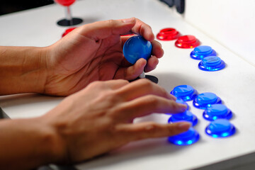 Detail of hands with arcade joystick playing old arcade video game console