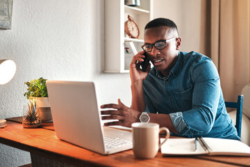 I always network. Cropped shot of a handsome young businessman sitting alone in his home office and talking on his cellphone.