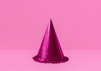 Party hat. Photo with copy space. Minimal style. Bright shining funny cap on pink backdrop