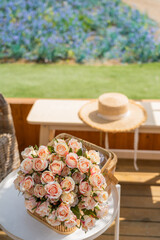 Flower in the picnis basket with summer hat with blue spring summer flowers blooming at the garden