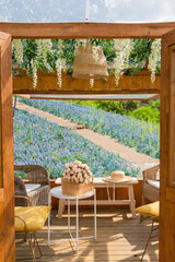 Flower bouquet in the picnic basket with summer hat with blue spring summer flowers blooming at the garden at the gazebo overlooking blue lavender flower field