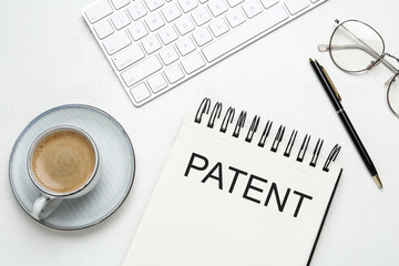 Notebook with word PATENT, keyboard, cup of coffee, pen and glasses on white table, flat lay