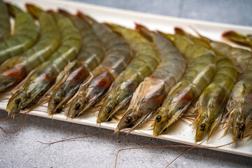 Raw shrimps lie on a white plate, close-up.