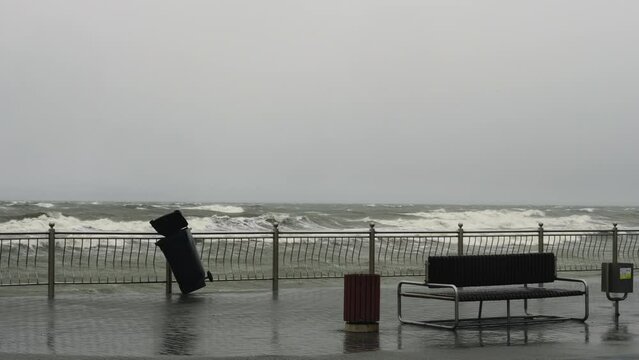 Hurricane ravages city. Gusty winds rock an empty trash can on the city's waterfront against a stormy sea. Hurricane Nadia Storm on the Baltic Sea. Water droplets on the lens