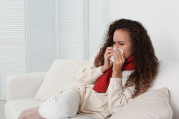 Sick African American woman with tissue at home