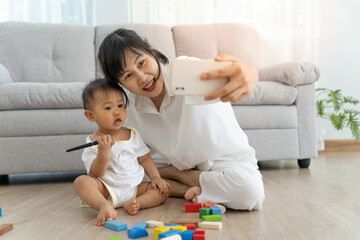 Happy single mom hugging daughter selfie together. Cute smiling daughter having fun taking pictures with lovely asian mother, warm relationship, mother and child.