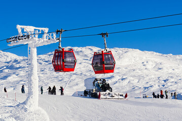 Ski resort in sunny day. Red cable car in a ski resort in the Alps. red gondola funicular in a ski...