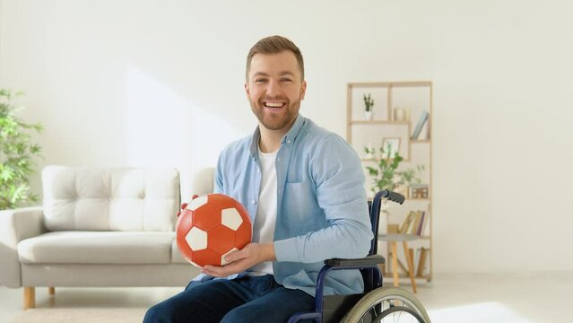 Happy disabled person in a wheelchair with a red ball in his hands before a walk