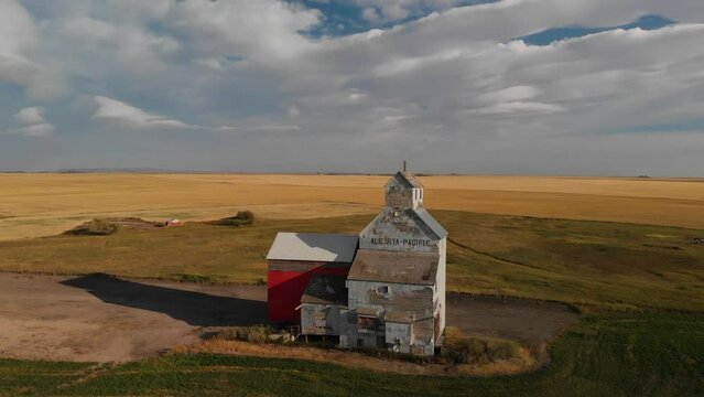 Drone backward shot of an old weathered grain elevator for storing wheat harvested on the rural area of Alberta, Canada on a cloudy evening.