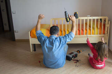 father and daughter celebrating after assembling the bedroom bed. Household do-it-yourself work