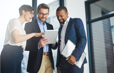 Digitizing business discussions. Shot of a team of colleagues using a digital tablet together at...