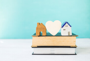 Obraz na płótnie Canvas House model with wooden heart on stack of book with space on blurred background, real estate and property business, house loan and legal