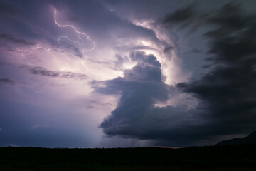 Lightning illuminates a supercell thunderstorm cloud in the night sky