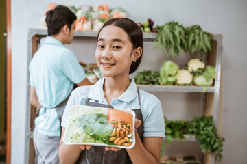 Smiling vegetable selling girl showing vegetables in a wrap