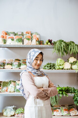 Girl in headscarf selling vegetables standing with folded hands