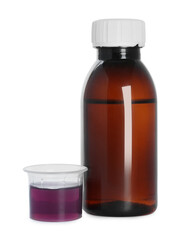 Bottle of cough syrup and measuring cup on white background