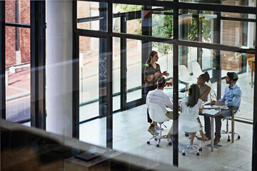 Leading her team through the meeting. Shot of a group of businesspeople having a meeting in a...