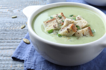 Delicious asparagus soup with croutons on grey wooden table, closeup